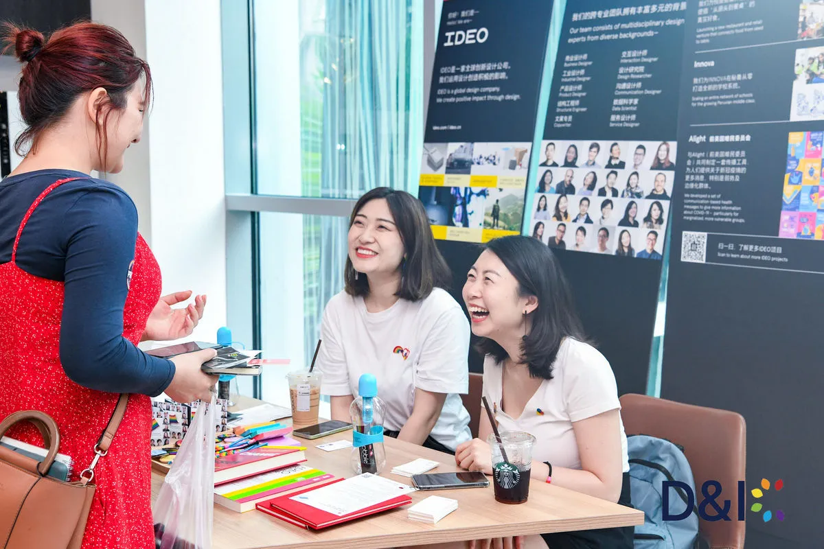 Two DNIC event hosts laughing with a visitor at an employer booth